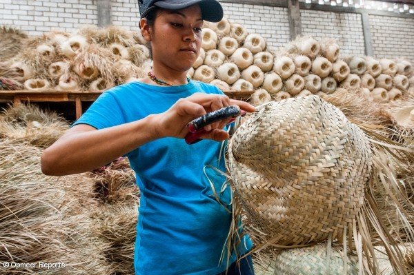 Un empleado de clientes de concreto Sombreros Sanchez cortando el exceso de paja de los sombreros de paja que produce. Sombreros Sanchez trabaja con proveedores locales para garantizar su fuerte impacto social.